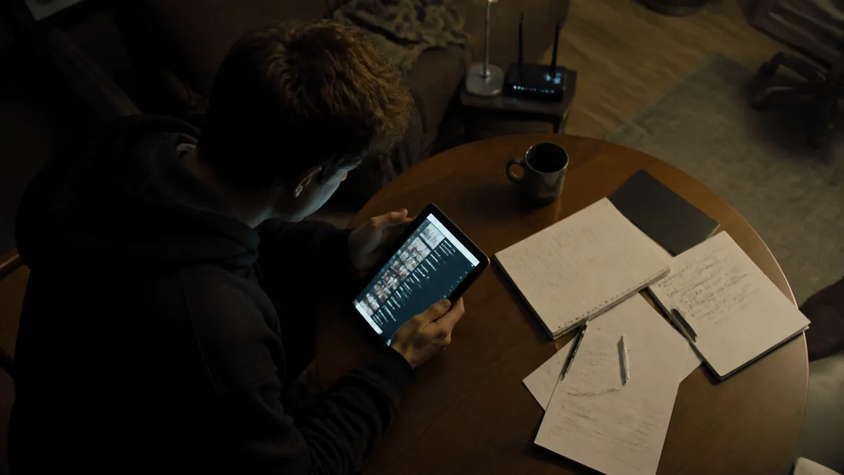 A person studies darknet market links on a tablet in a cozy apartment.